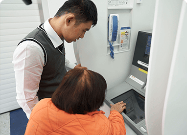 할머니께서 준영이에게 은행 ATM 사용 방법을 알려드리는 모습